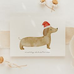 a card with a dachshund wearing a santa hat on it's head