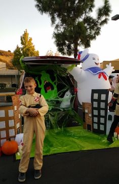 a young boy standing in front of a car decorated for halloween with ghost and pumpkins