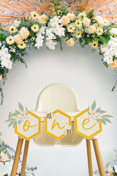 a white chair sitting under a wooden arch with flowers and bees on it's sides