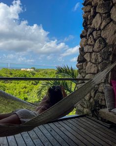 a woman laying in a hammock on top of a wooden deck