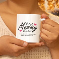 a woman holding a white coffee mug with the words best mommy ever printed on it