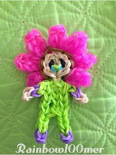 a crocheted doll is sitting on a green quilt with pink and purple flowers