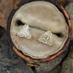 This pair of diamond stud style pierced earrings are each accented with one (1) triangular mixed cut diamond set into a three-prong setting. The earrings are finished with friction style backs.