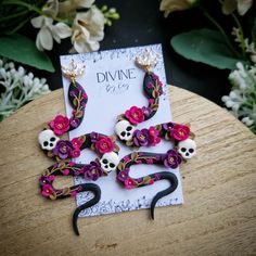 the earrings are decorated with flowers and skulls on them, while sitting on a wooden table