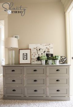 a gray dresser with pictures and plants on top