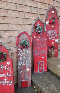 three red wooden christmas signs sitting on the side of a building