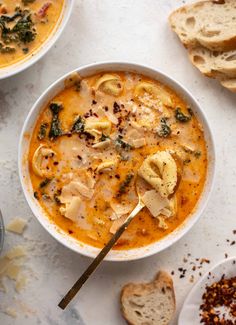 two bowls of soup with bread on the side