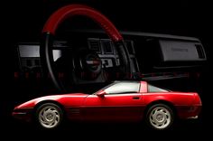 a red sports car parked in front of a black background with the steering wheel visible