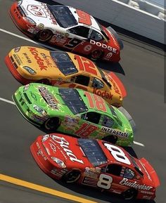 three racing cars lined up in a row on the track with numbers painted on them