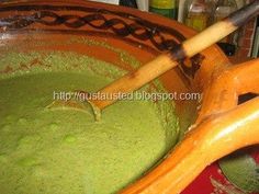 a wooden spoon in a bowl filled with green liquid