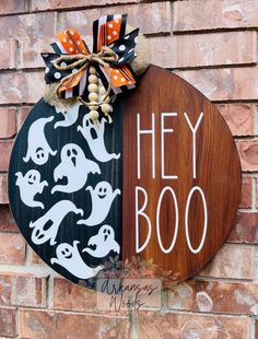 a wooden sign that says hey boo on it and has halloween decorations hanging from it