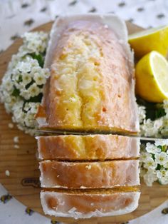 a loaf of lemon pound cake sitting on top of a wooden cutting board next to flowers