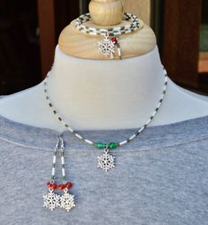 a necklace with snowflakes and beads is displayed on a mannequin