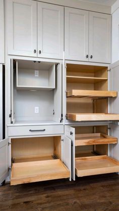 an empty kitchen with white cabinets and wooden shelves