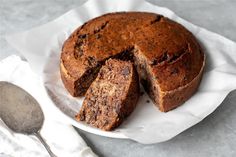 a chocolate cake with one slice cut out on a white plate next to a spoon