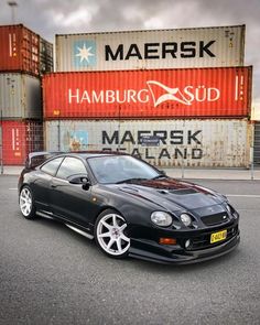 a black car parked in front of a shipping container