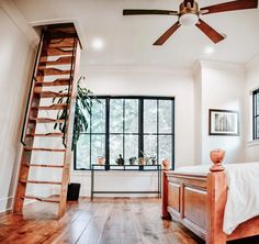 a bed room with a ladder to the ceiling next to a window and a bed