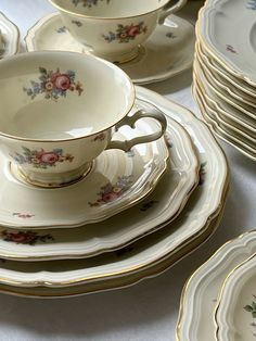 a table topped with lots of white and gold china cups and saucers on top of each other