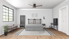 a bedroom with white walls and wood flooring has a bed, two chairs, a desk, and a ceiling fan