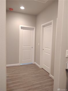 an empty room with two white doors and wood flooring in front of the door