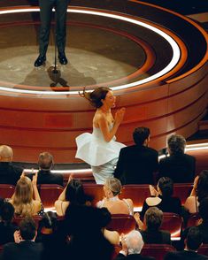 a woman standing on top of a stage in front of an audience