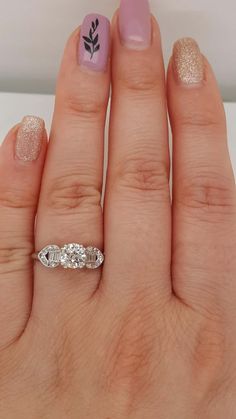 a woman's hand with pink and white nail polish holding a ring on her finger