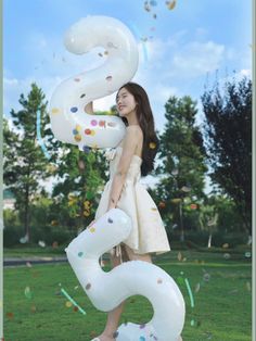 a woman in a white dress is holding balloons