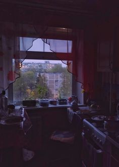 a kitchen with an open window looking out at the city outside in the evening time