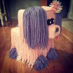 a dog made out of yarn sitting on top of a wooden floor