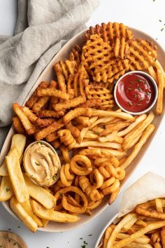 french fries with ketchup and mustard on a platter next to dipping sauce