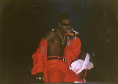 a man in a red outfit is on stage with his hands up to his mouth