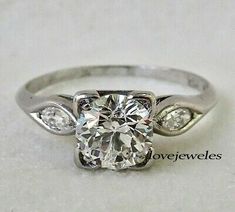 a white gold ring with an oval cut diamond and two small diamonds on the side