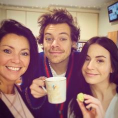 two women and a man posing for the camera with a coffee cup in front of them