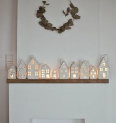 a fireplace with candles on top of it in front of a wreath and house decorations