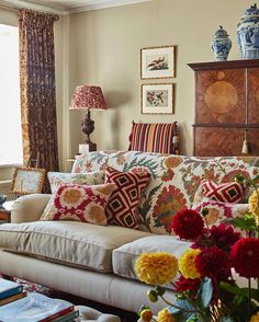 a living room filled with lots of furniture and flowers in vases on the coffee table