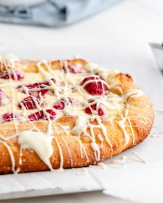 a pastry with white icing and raspberries on it sitting on a table