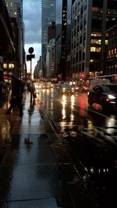 people are walking down the street in the rain