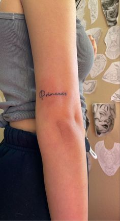 a woman's arm with the word princess tattooed on her left arm, in cursive font