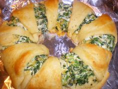 spinach rolls with cheese and sauce in a metal pan on top of aluminum foil