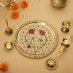 a plate with flowers painted on it surrounded by other dishes and cups, including spoons