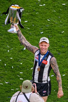 a man holding up a trophy on top of a field