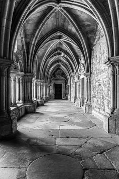 black and white photograph of the inside of an old building with stone columns, arches and arched doorways