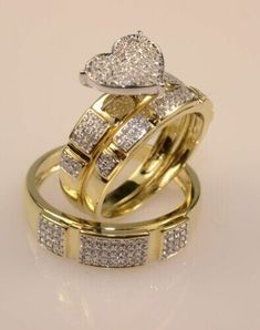 two gold wedding rings with diamond hearts on each one, set against a white background