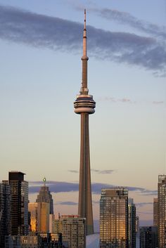 a tall tower towering over a city filled with tall buildings at sunset or dawn in the distance