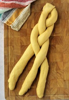 a wooden cutting board topped with uncooked long breadsticks on top of it