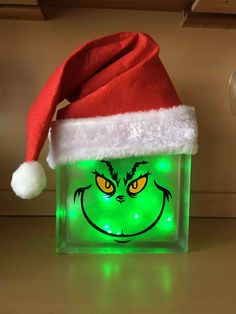 the grin face glows in green light up acrylic with a santa hat on