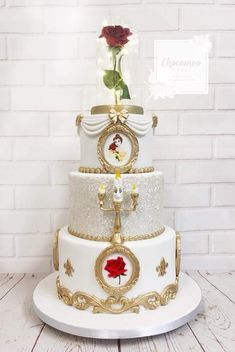 a white and gold wedding cake with a red rose on top