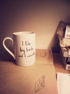 a coffee cup sitting on top of a pile of books next to some envelopes