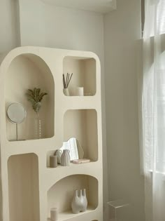 a white shelf with vases and other items on it