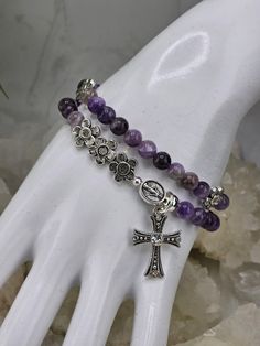 This beautiful rosary stretch bracelet is made with genuine purple Amethyst 6mm beads. The Miraculous Medal and sparkly rhinestone cross dangle from the front. 9mm Tibetan silver flower beads separate and accent the decade beads.  The bracelet measures 15 inches and wraps around the wrist twice.  Would make a perfect religious gift for that special person in your life! The Miraculous Medal was originally called the Medal of the Immaculate Conception, but because of the numerous accounts of miracles by those who wore it people began to call it the Miraculous Medal, and the name stuck. The Medal is a visual reminder of our salvation through Jesus Christ. The purple color of amethyst has long been a symbol of peace, cleansing and calming energy. The crystals represent purification and connect Rhinestone Cross, Miraculous Medal, Catholic Gifts, Religious Jewelry, Religious Gifts, Silver Flowers, Purple Amethyst, Rosary, Beaded Flowers